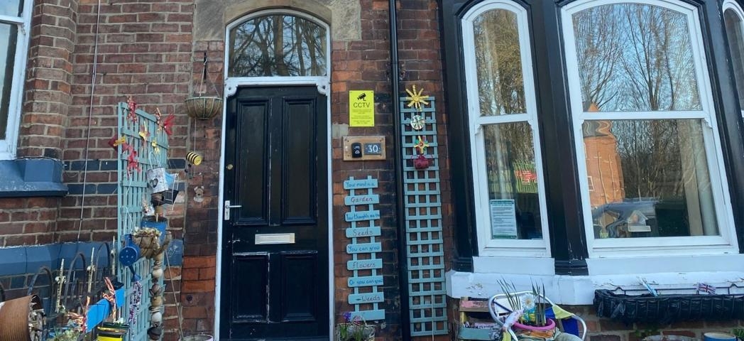A very homely array of items adorn the outside of the Victorian styled property. Teal blue painted wall trellising and personalised plaques are placed around the doorway and as a separation between the neighbouring property.