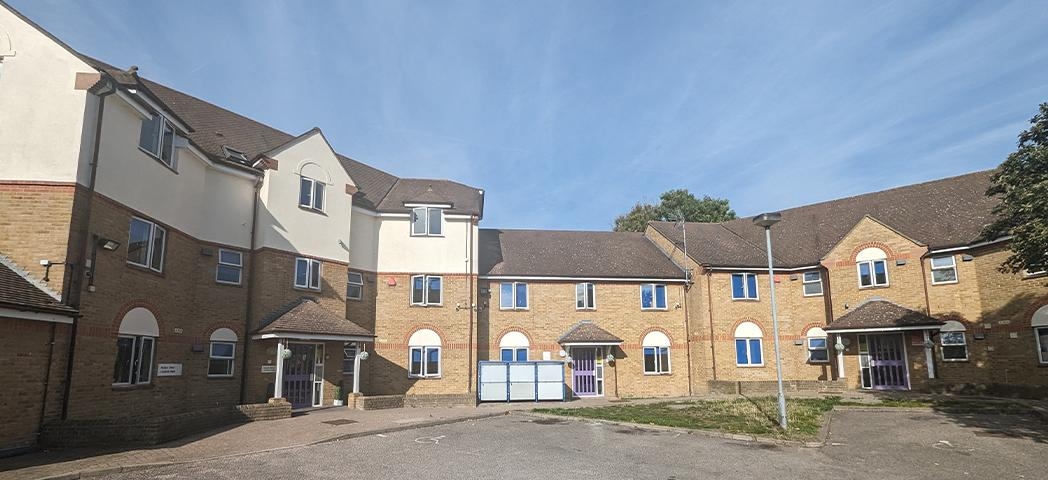Brown brick and white terraced houses surrounding a grey gravel courtyard