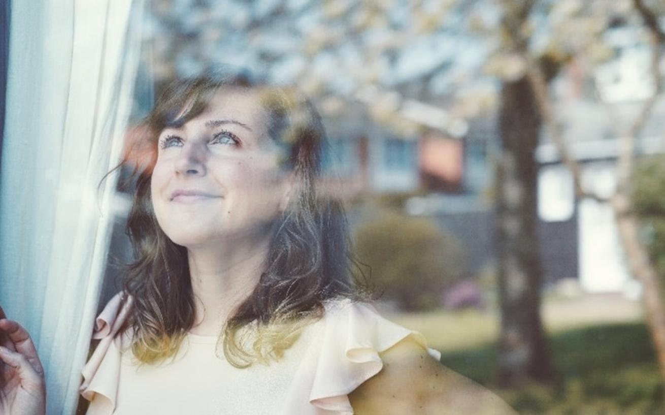A woman looking hopeful, looking out of the window