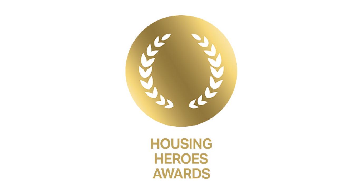 Gold circular emblem with laurel leaves and text below reading 'HOUSING HEROES AWARDS'