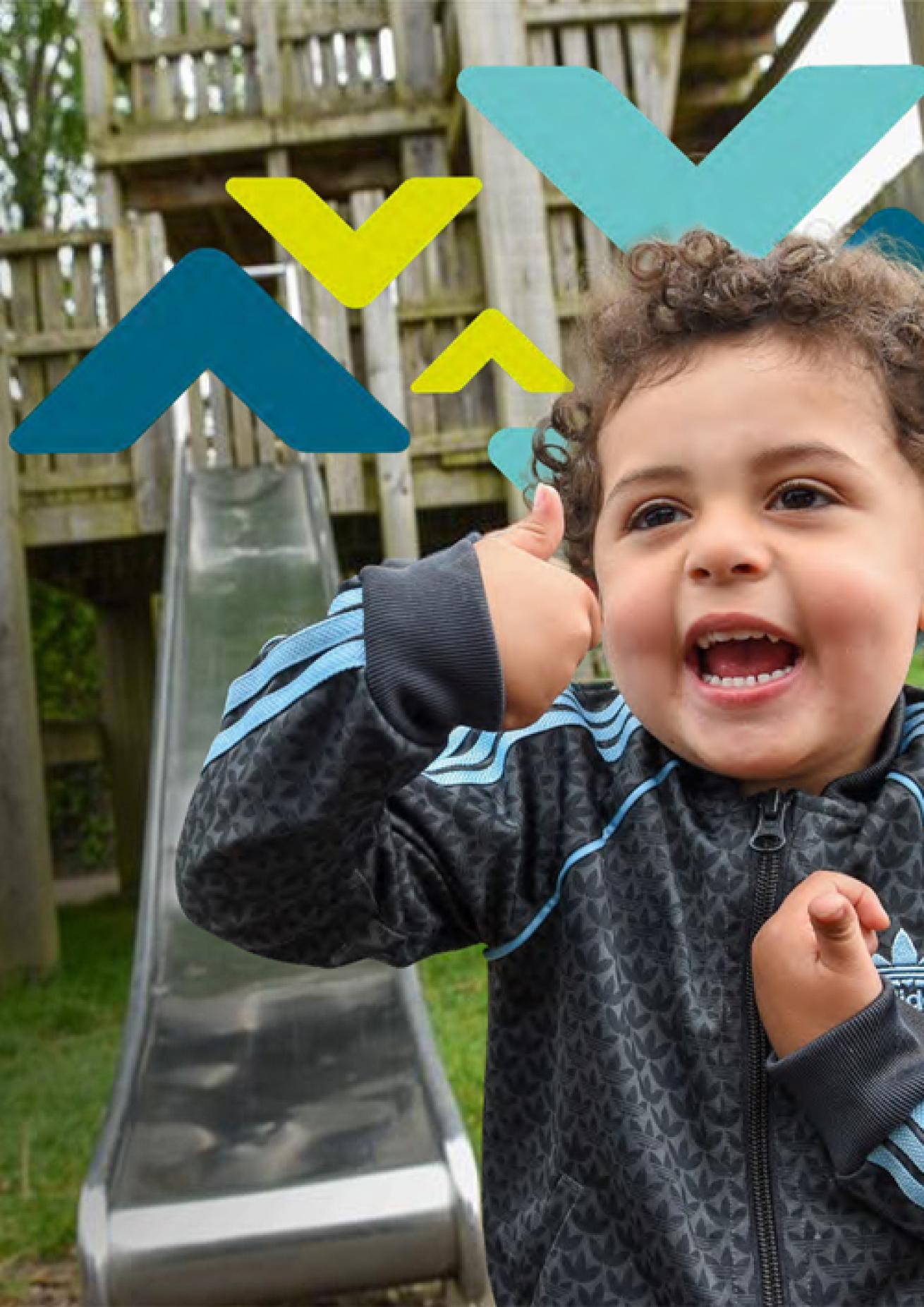 Child in Adidas jacket gives thumbs-up in front of playground slide, with colourful geometric shapes overlaid.