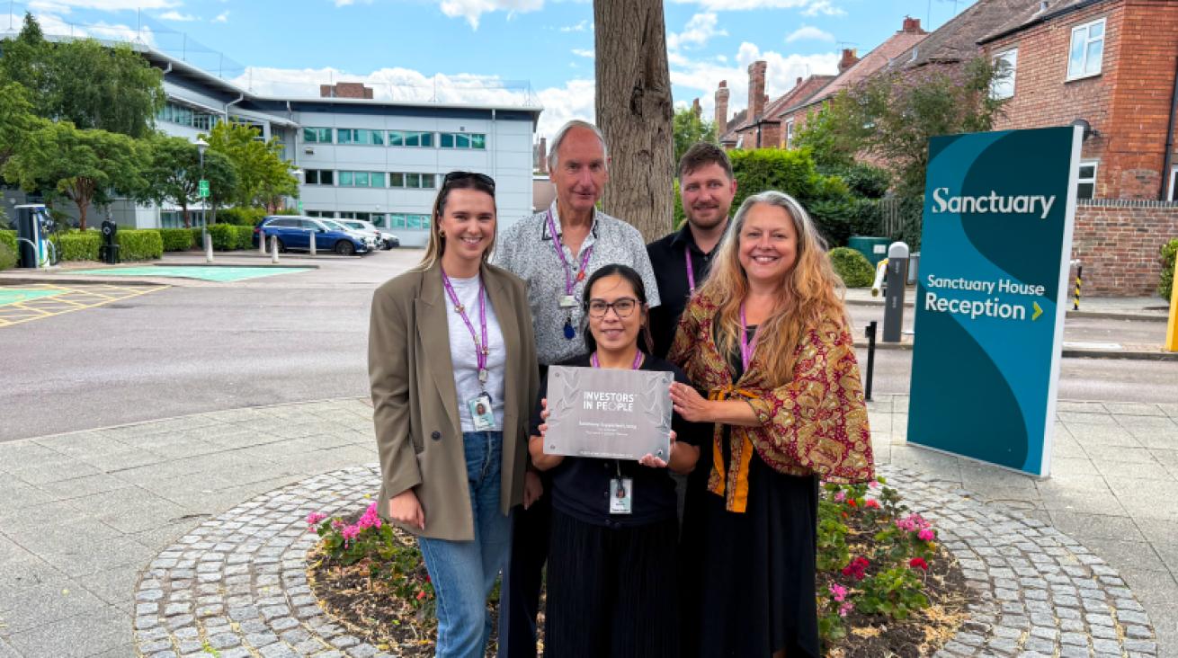 Five Sanctuary colleagues standing outside Sanctuary House holding an Investors in People Platinum accreditation plaque