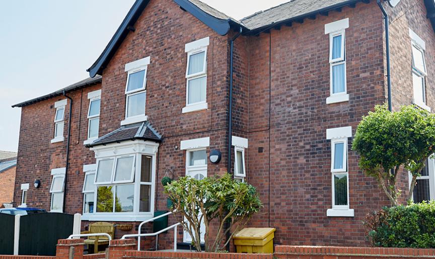 Characteristic, weathered dark brick residential home, with accessible entry to the care facility. 