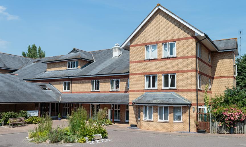 A contemporary red and yellow brick built retirement community property, set across a multi elevation floor plan, set in a well maintained driveway with circular plant feature.