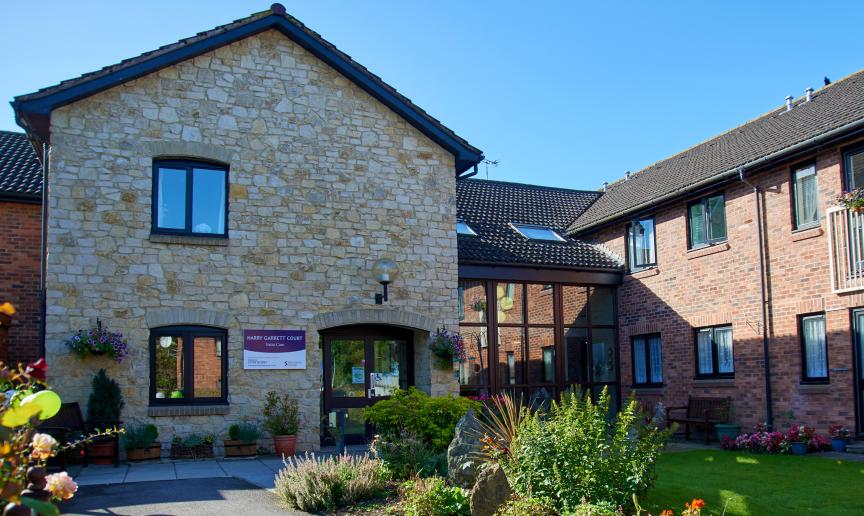 A stunning blend of stone materials for the façade of the entrance to Harry Garrett Court, the dark wooden framed window and doors contrast beautifully, to the left there is a wonderful floor to ceiling walkway linking to the traditional red brick extension. The well maintained gardens guide you to the entranceway in an inviting manner.