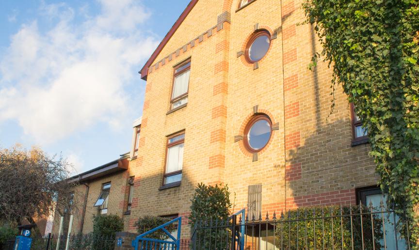Yellow bricked multi storey supported housing property at John Pounds House in Wandsworth. With a focal feature of circular windows above the entry way.