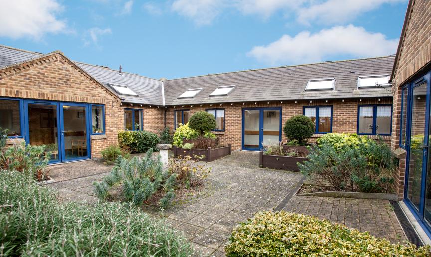 A single storey property, with a small but flourishing courtyard area. The building is built in a 50’s style brown brick built style. The framing for the doors and windows are all in a royal blue adding a pop of colour to the outside area. Skylights have been placed all along the roof.