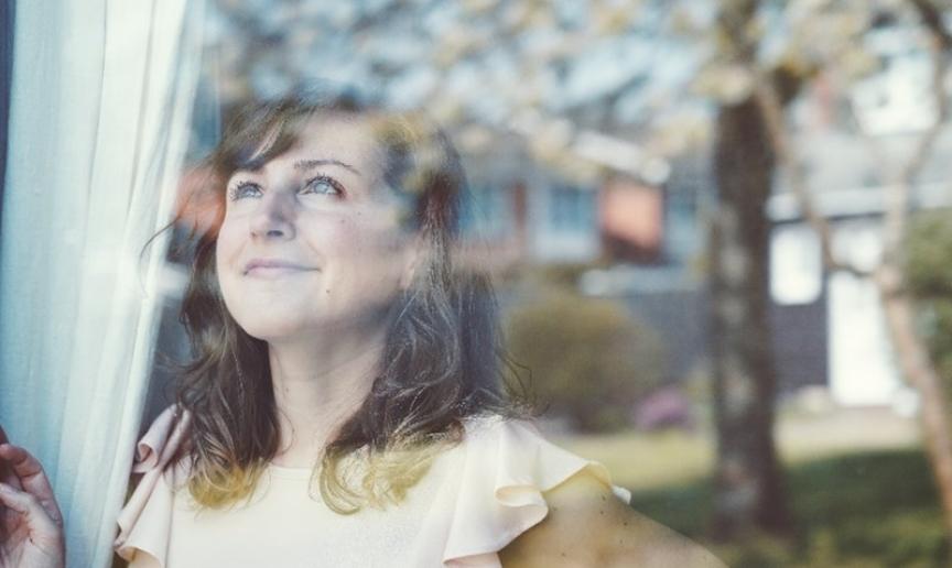 A woman looking hopeful, looking out of the window