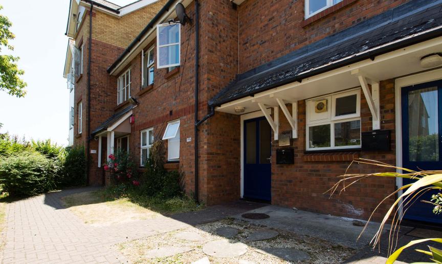 Detached, two storey supported housing property. With scattered windows and centralised blue door and porch.