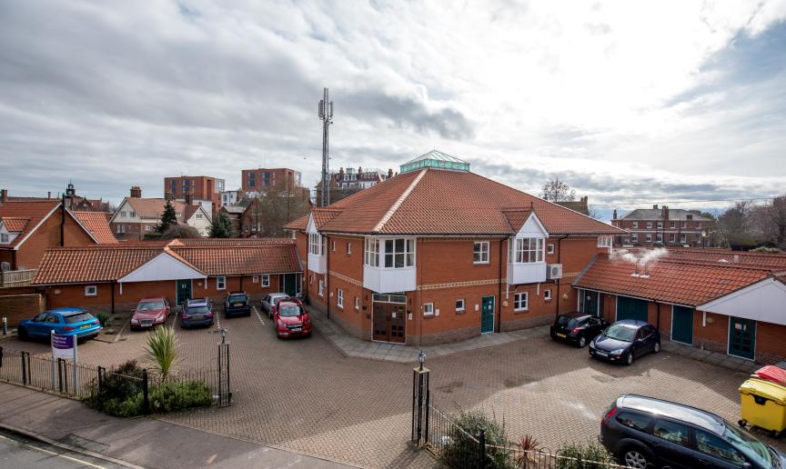 External image of Montague Road Care home, with a car park in front of the large building and high rise buildings in the distance