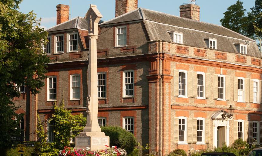 An impressive stone built stepped memorial in front of a yellow and orange bricked stately home in Dedham.