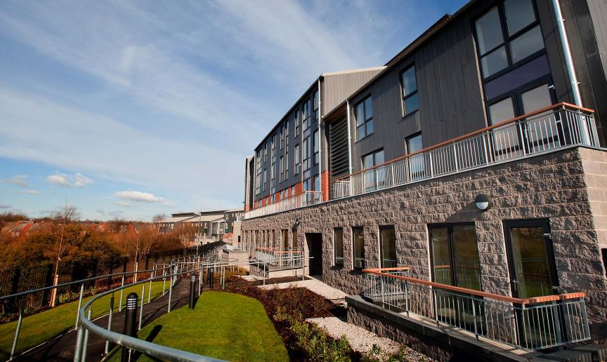A fully accessible walkway around the rear of the property with views of the mature trees and grassed areas.