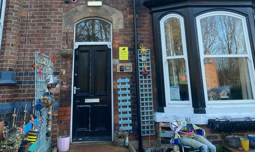 A very homely array of items adorn the outside of the Victorian styled property. Teal blue painted wall trellising and personalised plaques are placed around the doorway and as a separation between the neighbouring property.