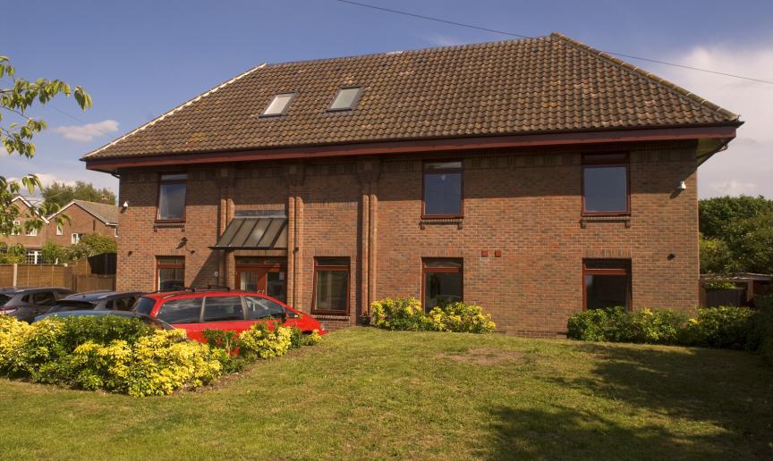 Red brick, flat topped roofed building with a lawn in front.