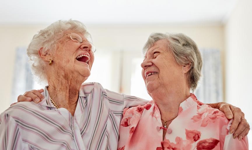 Two happy elderly women embracing each other at home