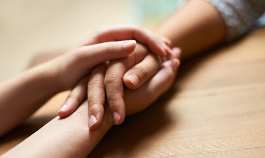 Close up of a white person holding the right hand of a mixed race person