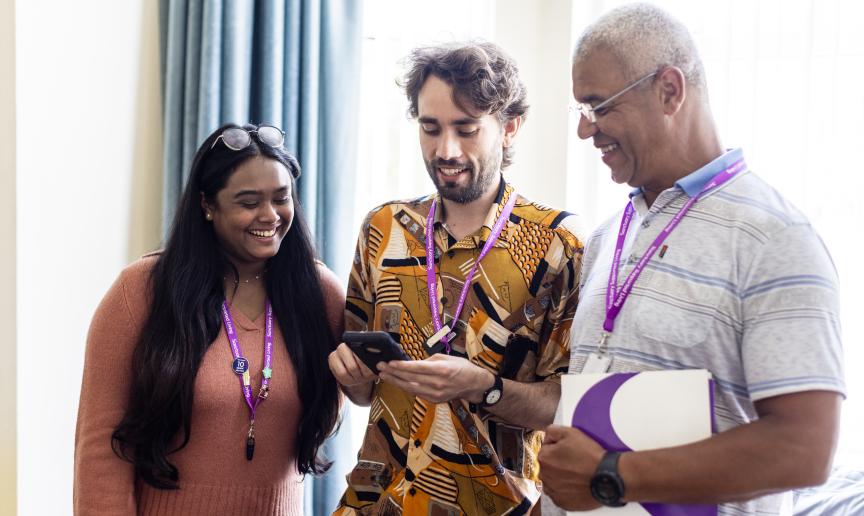 Three Sanctuary Supported Living staff members smiling while looking at a mobile phone