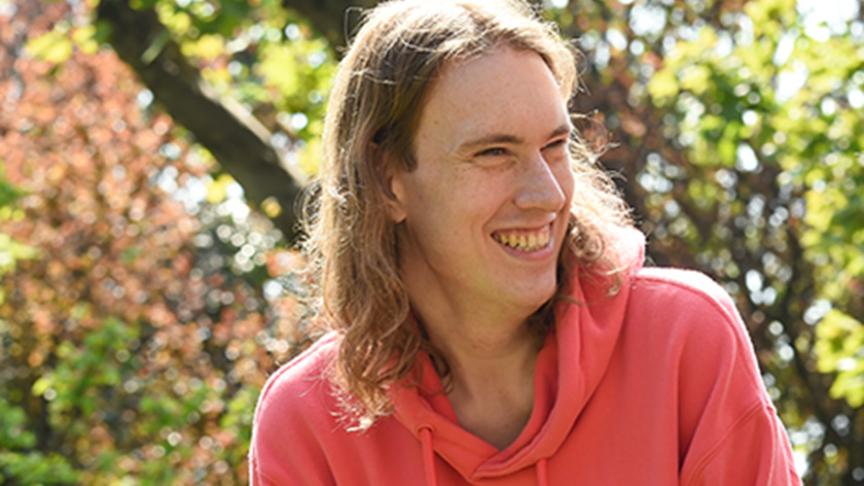SSL resident smiling, photographed outside by a tree