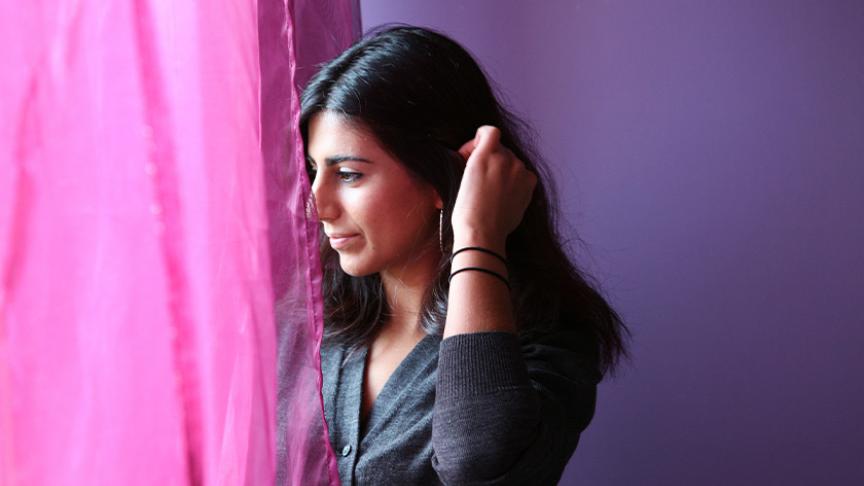 Stock image of a woman looking through a curtain