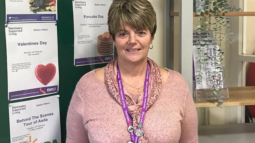 Sanctuary staff member at Station Mews, photographed in front of the noticeboard at Station Mews scheme