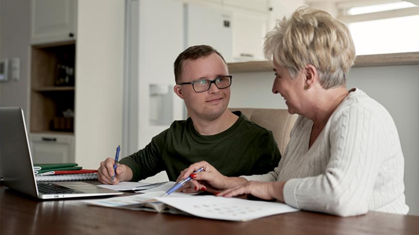 A stock image of two people sat in front of a laptop, planning something