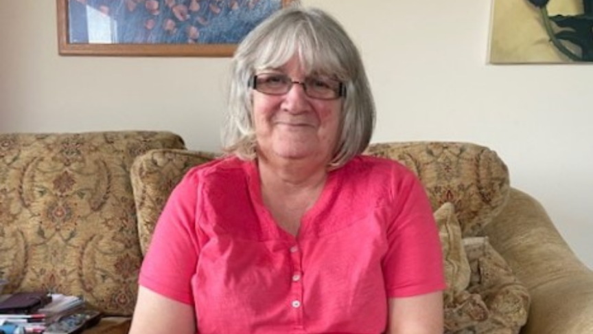 A woman sits and smiles in an armchair
