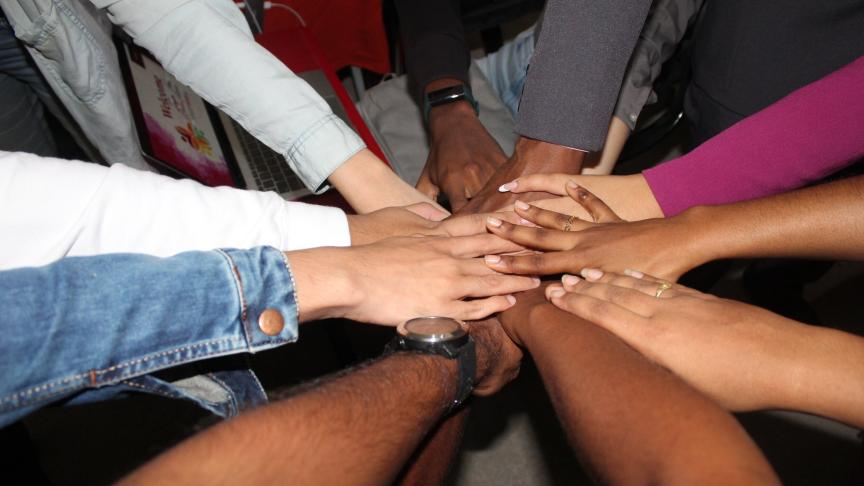 An image of 9 people's hands altogether in a circle
