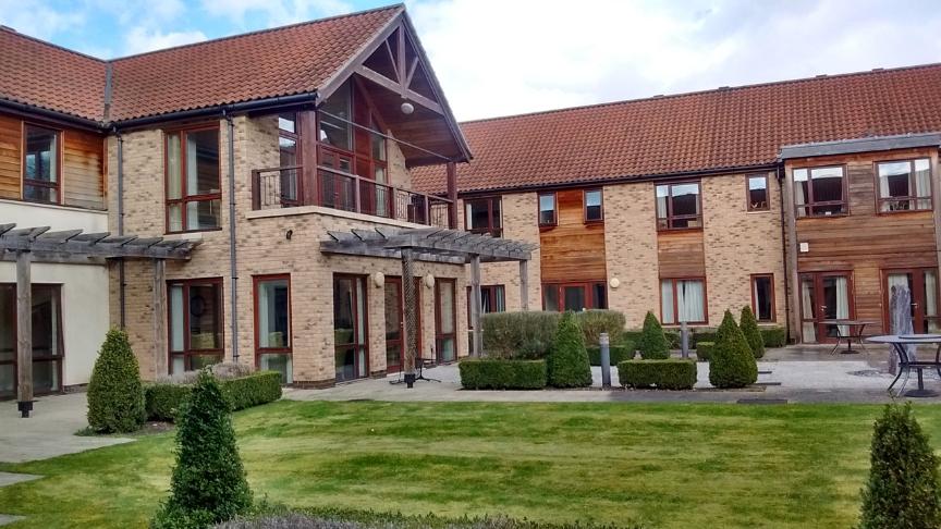 Exterior of Exning Court a two storey purpose built retirement community with large windows and a first floor balcony