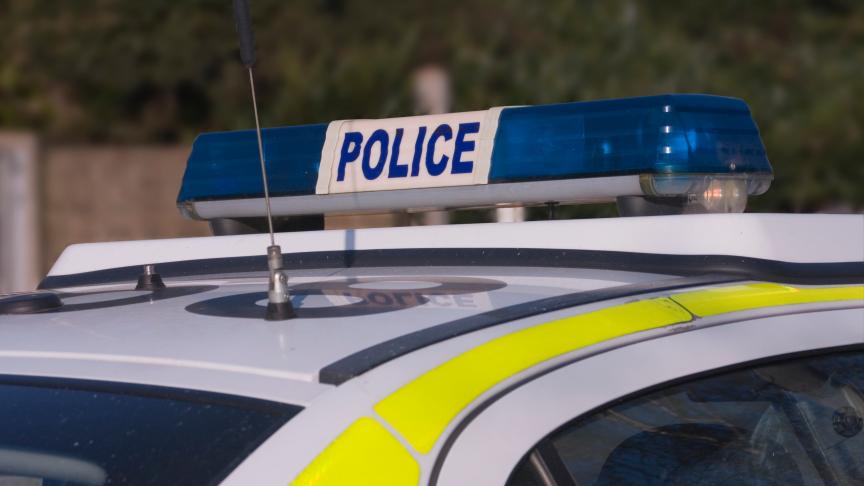 Close up of the top of a police car with white and neon yellow body work and blue lights on top