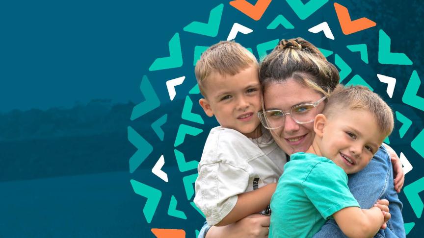 A young woman with glasses is smiling and hugging two young boys, one on each side