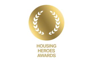Gold circular emblem with laurel leaves and text below reading 'HOUSING HEROES AWARDS'