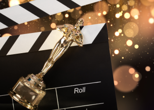 A gold Oscar award lay across a cinematic clapperboard.