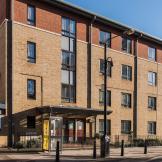 A four storey new-build brick apartment block, located by a main road with gated access to the entrance and a secure gated carpark. 