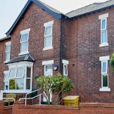 Characteristic, weathered dark brick residential home, with accessible entry to the care facility. 