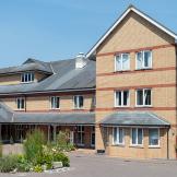 A contemporary red and yellow brick built retirement community property, set across a multi elevation floor plan, set in a well maintained driveway with circular plant feature.