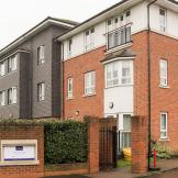 The newly built brick, three storey retirement community. With a large hedge wrapping the front of the property for privacy, an iron gate for pedestrians and a speed restricted driveway.  
