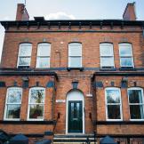 Majestic well weathered brick building, with perfectly symmetrical exterior features including chimneys and windows. As well as a central stepped entry to the front door.