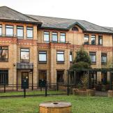 The characteristic, yellow brick built corner plot building, with a decorative red brick addition above the storey elevation wrapping the property and a magnitude of dark framed windows decorating the exterior. The centre of the property holds a well-maintained grassed area with brick paved walkway, as well as wooden pergola covering the entranceways into the property.
