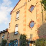 Yellow bricked multi storey supported housing property at John Pounds House in Wandsworth. With a focal feature of circular windows above the entry way.