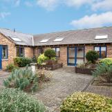 A single storey property, with a small but flourishing courtyard area. The building is built in a 50’s style brown brick built style. The framing for the doors and windows are all in a royal blue adding a pop of colour to the outside area. Skylights have been placed all along the roof.