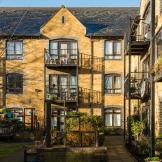 Traditional yellow bricked property with grey bricked framing around the windows and doorways. Iron barred balconies are attached to the large curved toped patio doorways. Wheelchair access pathways run around the perimeter of the building.