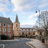 St Peters Church in Mansfield town centre with vicarage and one way road passing through village.