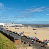 Golden sandy beach, sectioned off by a short pier. The small bricked beach huts line the promenade.