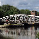 Weathered silver, curved metal bridge creating access over the river.