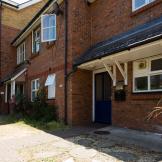Detached, two storey supported housing property. With scattered windows and centralised blue door and porch.