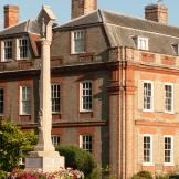 An impressive stone built stepped memorial in front of a yellow and orange bricked stately home in Dedham.