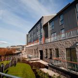 A fully accessible walkway around the rear of the property with views of the mature trees and grassed areas.