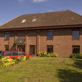 Red brick, flat topped roofed building with a lawn in front.