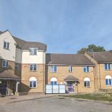 Brown brick and white terraced houses surrounding a grey gravel courtyard